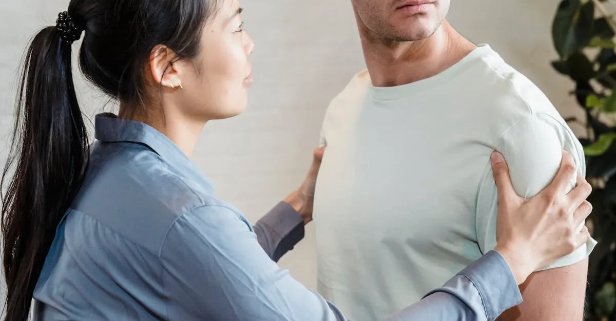 downloaded-image Woman in a blue shirt holds a man's shoulders, guiding him in a posture check, in a bright room.