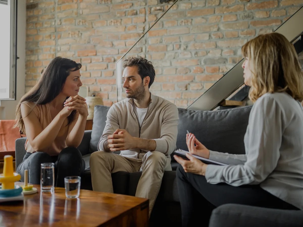 1 Couple sitting together in therapy, looking thoughtful rather than distressed.