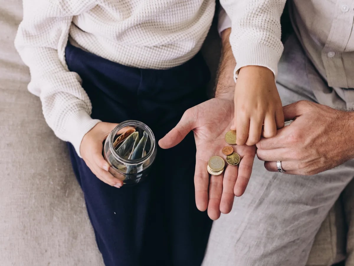 money-revenge-after-infidelity-1 Couple saving money together: coins added to a glass jar held over a couch.