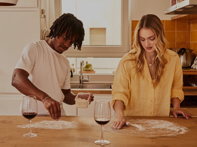 A couple cooking dinner together, both looks like they respect each other while doing chores together.